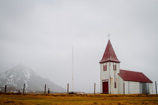 Antigua iglesia con techo rojo en un campo bajo un cielo nublado en Islandia