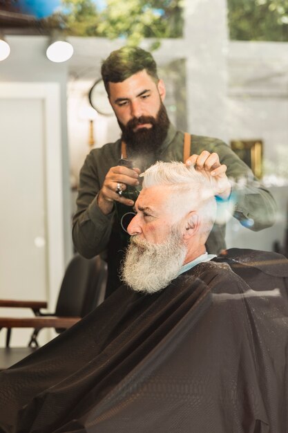 Antiguo cliente brutal cortando cabello en la barbería