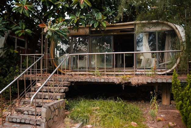 Antiguo edificio abandonado con ventanas de vidrio en un jardín en Wanli UFO Village, Taiwán