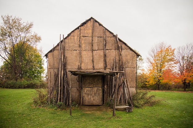 Antiguo granero de madera rodeado de árboles en un campo bajo un cielo nublado durante el día