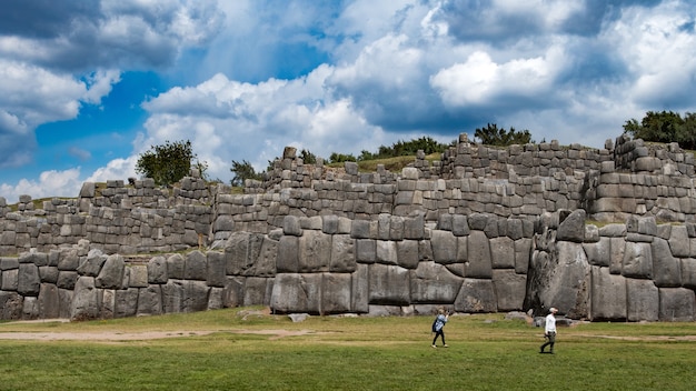 Foto gratuita antiguo muro de piedra y turistas cerca de él con un cielo azul