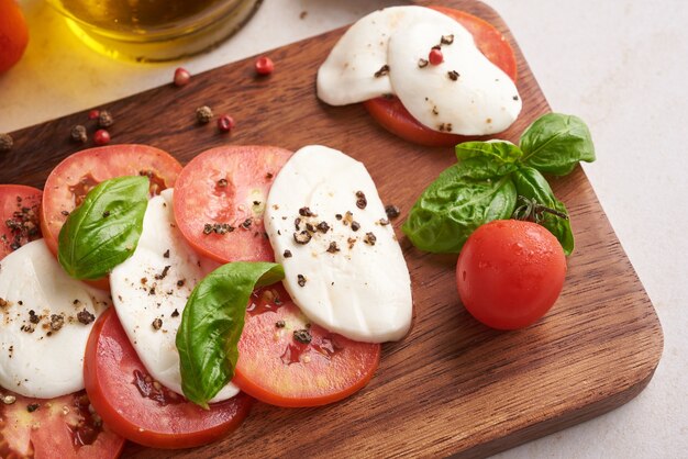 Antipasto de ensalada italiana fresca llamado caprese con mozzarella de búfala, tomates en rodajas y albahaca con aceite de oliva. Ingredientes para ensalada caprese vegetariana. Comida italiana. vista superior. Estilo rústico.