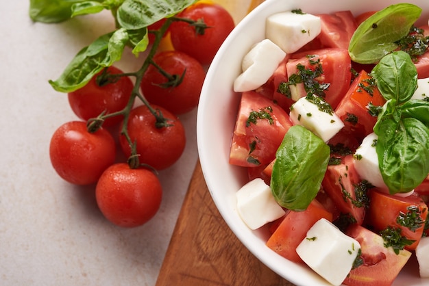 Antipasto de ensalada italiana fresca llamado caprese con mozzarella de búfala, tomates en rodajas y albahaca con aceite de oliva. ingredientes para ensalada caprese vegetariana. comida italiana. vista superior. estilo rústico.