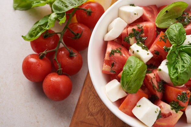 Antipasto de ensalada italiana fresca llamado caprese con mozzarella de búfala, tomates en rodajas y albahaca con aceite de oliva. Ingredientes para ensalada caprese vegetariana. Comida italiana. vista superior. Estilo rústico.