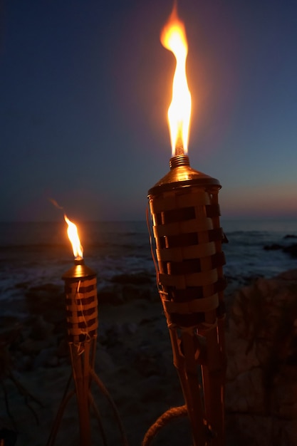 Antorchas de noche con llamas amarillas y reflejos.