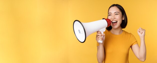 Anuncio feliz mujer asiática gritando fuerte en megáfono reclutando protestando con altavoz en mano