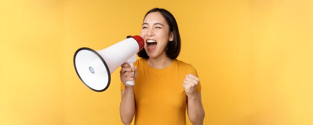 Anuncio feliz mujer asiática gritando fuerte en megáfono reclutando protestando con altavoz en mano