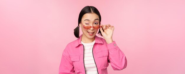 Anuncio de gafas elegante chica asiática moderna toca gafas de sol lleva poses rosadas contra el estudio b