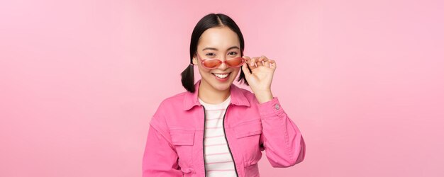 Anuncio de gafas Elegante chica asiática moderna toca gafas de sol usa poses rosas contra el fondo del estudio Copiar espacio