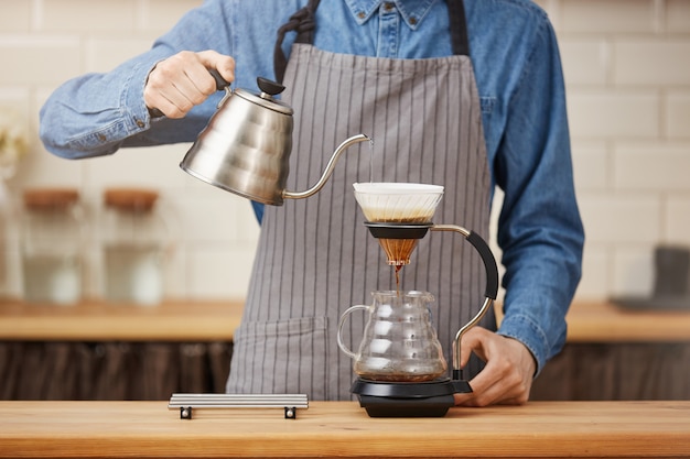 Aparatos de elaboración de café. Camarero masculino que prepara el café del pouron en la barra.