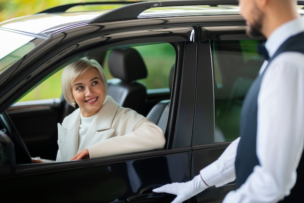 Foto gratuita aparcacoches ayudando a mujer a aparcar su coche