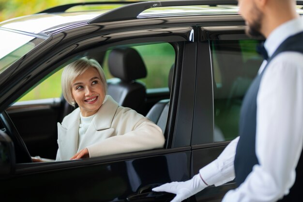 Aparcacoches ayudando a mujer a aparcar su coche