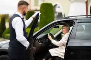 Foto gratuita aparcacoches ayudando a mujer a aparcar su coche