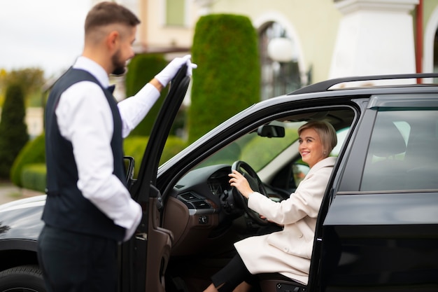 Aparcacoches ayudando a mujer a aparcar su coche