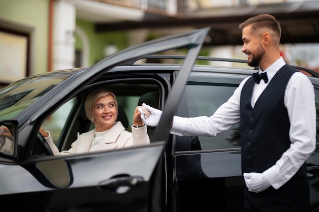 Aparcacoches ayudando a mujer a aparcar su coche