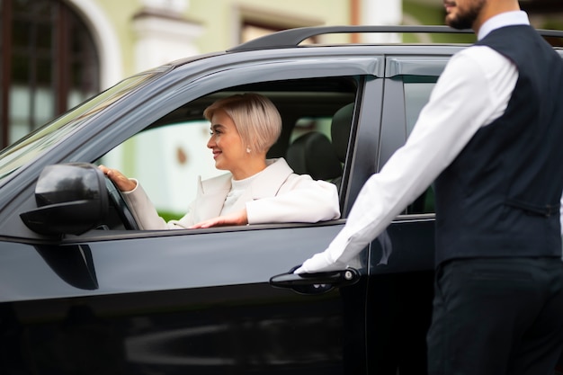 Aparcacoches ayudando a mujer a aparcar su coche