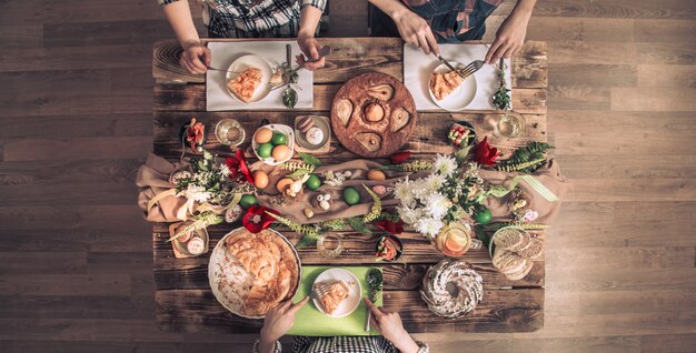 Apartamento-fiesta de amigos o familiares en la mesa festiva con carne de conejo, verduras, pasteles, huevos, vista desde arriba.