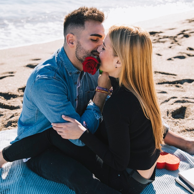 Apasionada pareja jugando con rosa en la playa