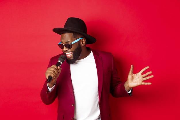 Apasionado cantante masculino negro actuando contra rojo