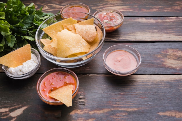 Aperitivo de nachos con salsas en mesa.