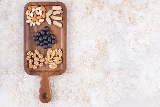 Aperitivo que sirve con pequeños montones de nueces y dulces en una tabla.