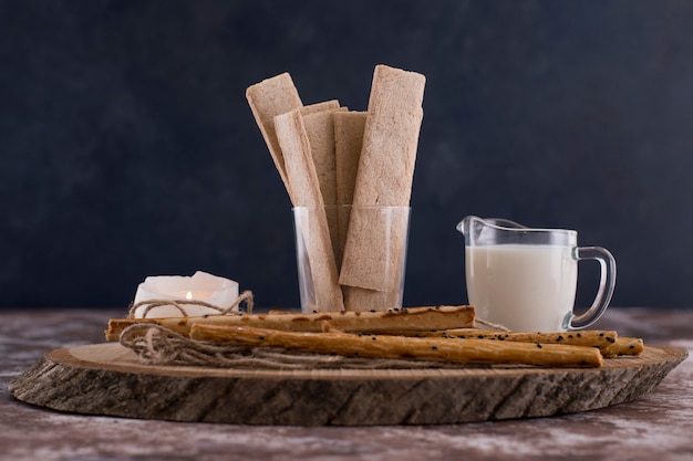 Aperitivos y galletas con un vaso de leche en una mesa de mármol negro.