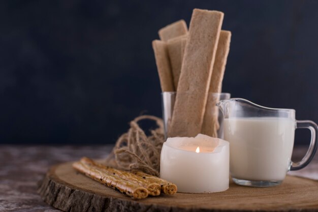 Aperitivos y galletas con un vaso de leche en una tabla de madera.