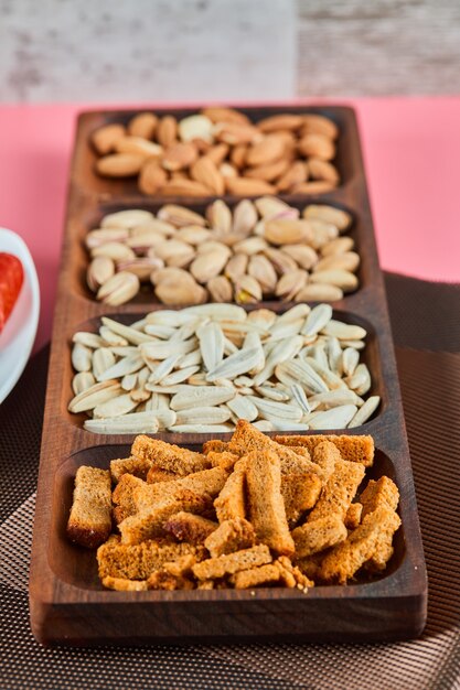 Aperitivos variados en la mesa rosa. Pistachos, pipas de girasol, almendras, galletas.