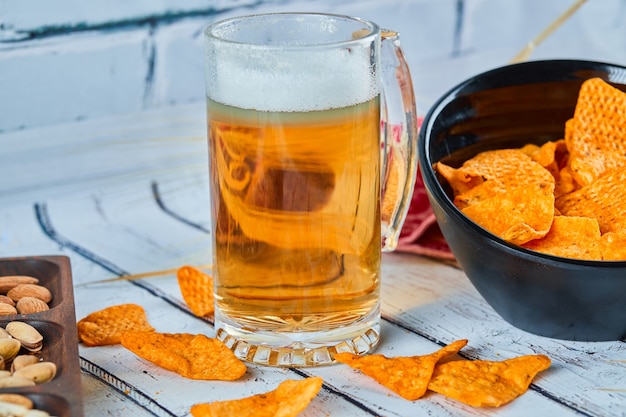 Aperitivos variados, patatas fritas y un vaso de cerveza en la mesa azul.