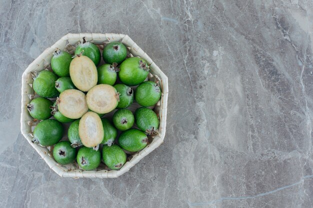 Apetitosa canasta de jugosas feijoas sobre mármol.