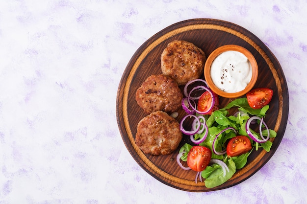 Apetitosa chuleta de carne y ensalada de tomate con rúcula