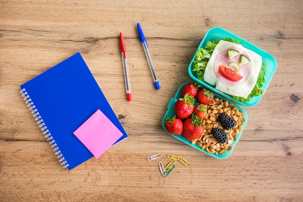 Foto gratuita apetitosa comida escolar y papelería sobre mesa.