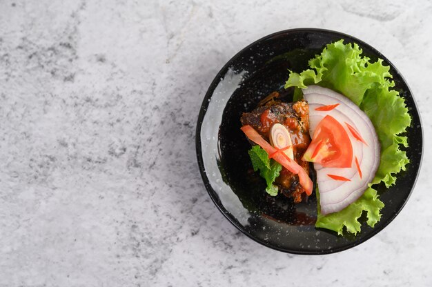 Apetitosa ensalada de sardina enlatada picante en salsa picante en un tazón de cerámica negra