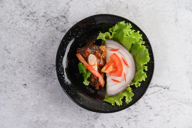 Apetitosa ensalada de sardina enlatada picante en salsa picante en un tazón de cerámica negra