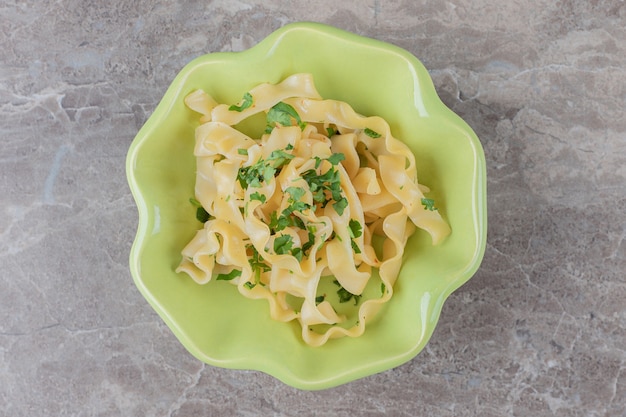 Apetitosa pasta de espagueti italiana clásica en el cuenco, sobre la superficie de mármol.