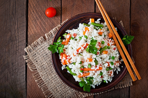 Foto gratuita apetitoso arroz saludable con verduras en plato blanco sobre una mesa de madera.