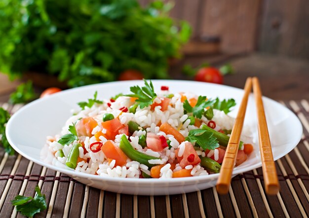 Apetitoso arroz saludable con verduras en plato blanco sobre una mesa de madera.