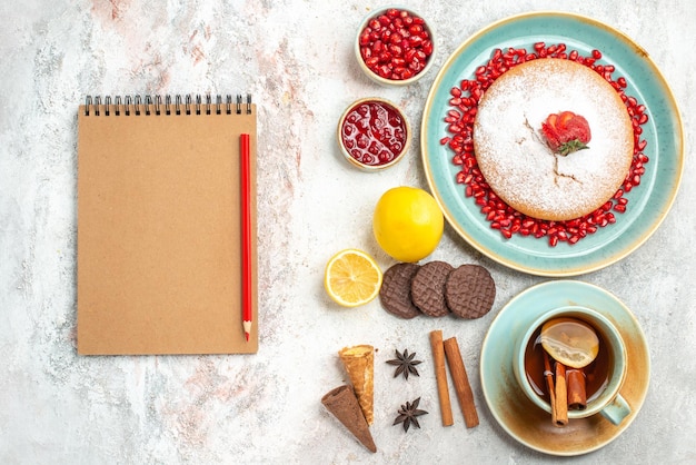 Foto gratuita el apetitoso bizcocho una taza de té y el bizcocho junto al cuaderno y el lápiz