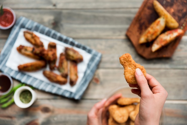 Apetitoso bocadillo de pollo con miga sostenido por persona