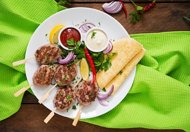 Foto gratuita apetitoso kofta kebab (albóndigas) con salsa y tacos de tortillas en un plato blanco