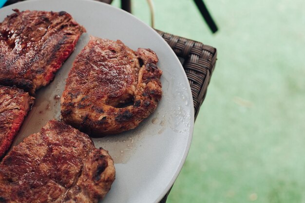 Apetitoso medio filete fresco a la parrilla asado en un plato blanco rodeado de hierba verde