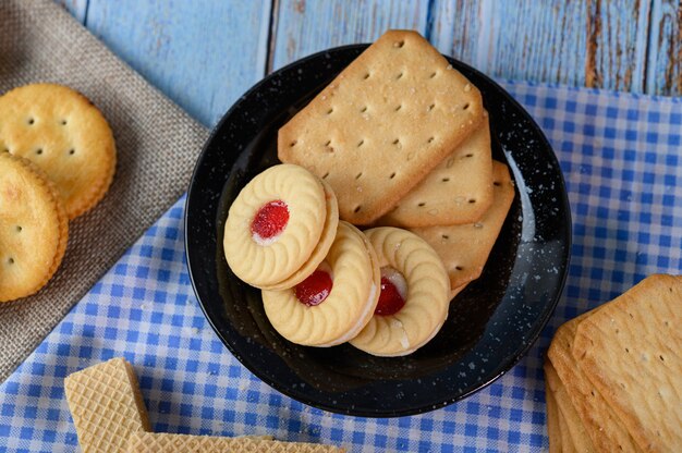 Apila muchos tipos de galletas en un plato y ponlas sobre una mesa de madera.