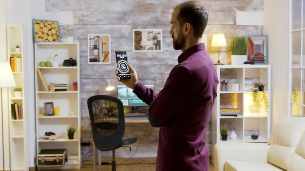 Aplicación de casa inteligente con un hombre que enciende las luces con un comando de voz en su teléfono