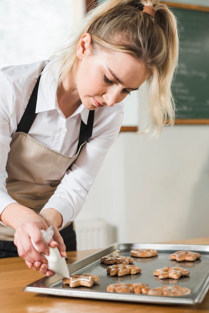 Foto gratuita aplicar crema en las galletas horneadas sobre la bandeja para hornear.