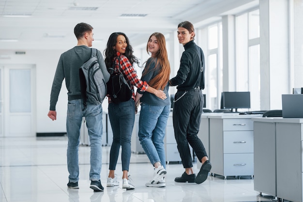 Apoyándose unos a otros. Grupo de jóvenes caminando en la oficina en su tiempo de descanso