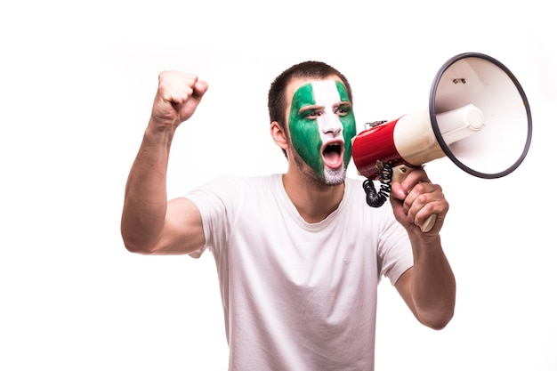 El apoyo del ventilador del equipo nacional de Nigeria con la cara pintada gritar con altavoz aislado sobre fondo blanco.