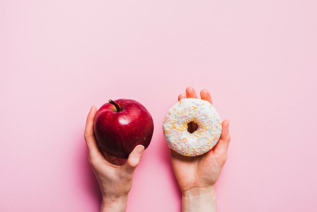 Apple y donut en fondo rosa