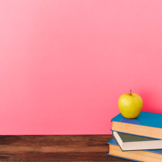 Apple y libros cerca de la pared rosa