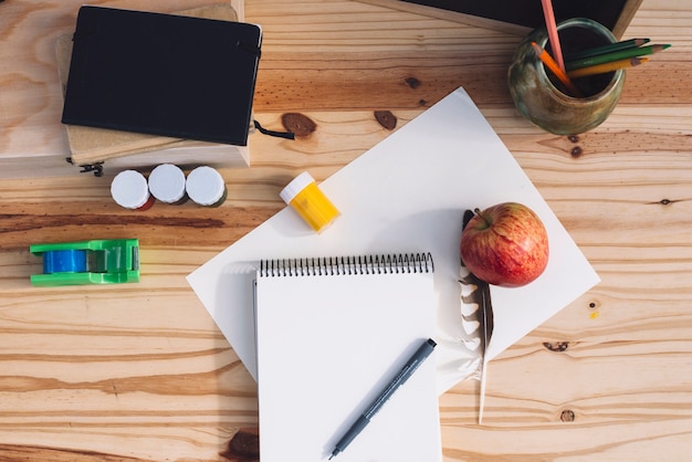 Apple y pluma cerca de suministros de dibujo