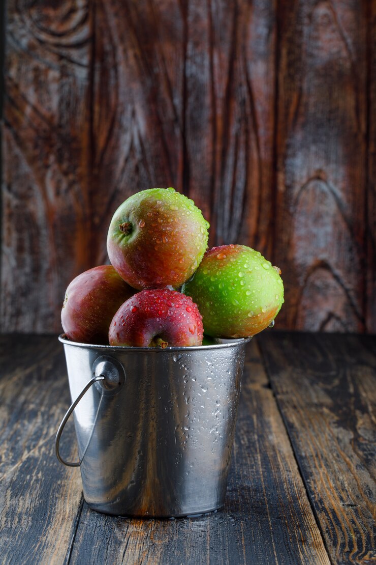 Photo Gratis apples in a mini bucket on old wooden background. side view.